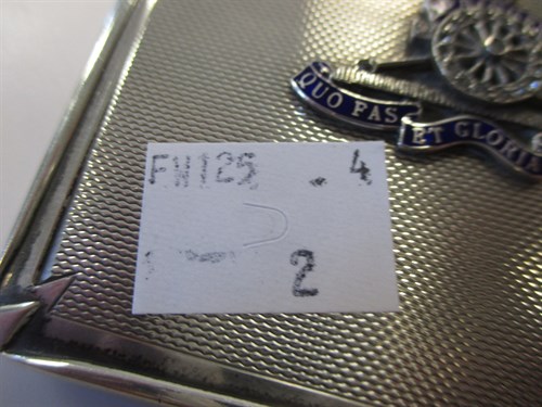 Lot 289 - A silver powder compact with an applied badge...