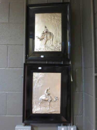 Lot 259 - A pair of ebony framed white metal panels, one...