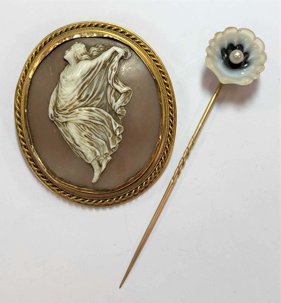 Lot 24 - A shell cameo brooch and a banded agate and pearl set stick pin