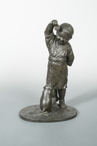 Lot 91 - A Japanese bronze group of a boy teasing a puppy dog with a biscuit, Late Meiji Period (1868-1912)