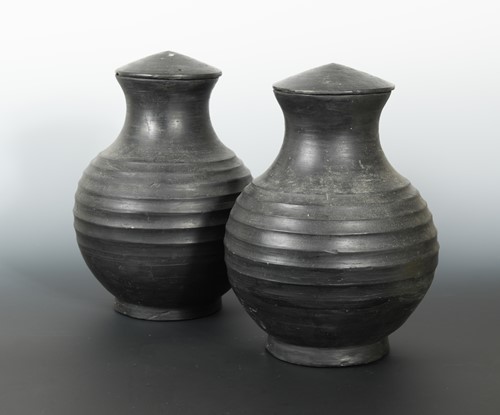 Lot 336 - A pair of Chinese burnished pottery lidded vases, with deeply ribbed bodies, perhaps Han Dynasty