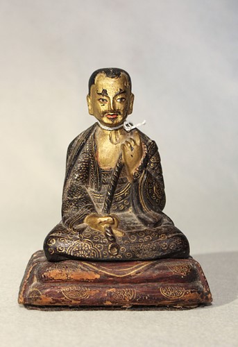 Lot 390 - A Tibetan painted wood seated figure of a monk, 18th/19th century