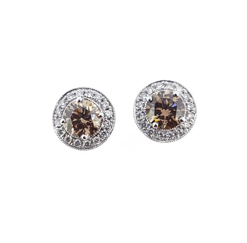 Lot 187 - A pair of fancy brown and white diamond halo style cluster ear studs