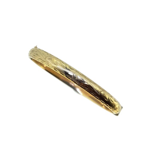 Lot 64 - A 9ct gold half engraved hinged snap bangle