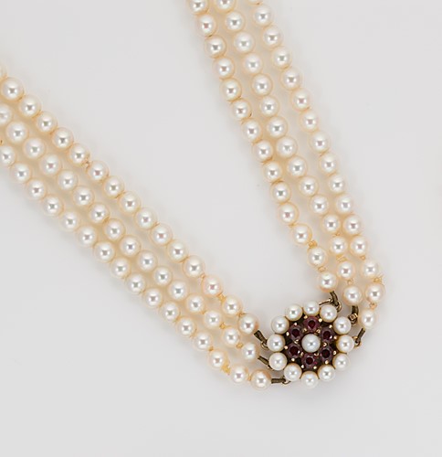 Lot 42 - A triple row necklace of cultured pearls with a garnet clasp