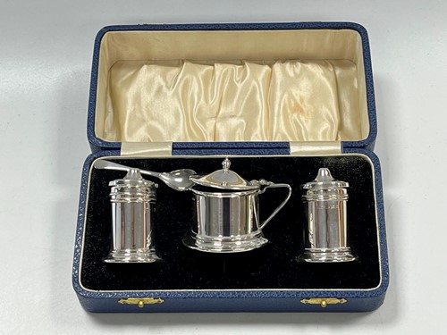 Lot 381 - A silver three-piece cruet set with blue glass...