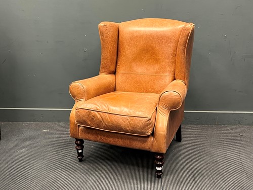 Lot 643 - A modern tan leather wing armchair on turned...