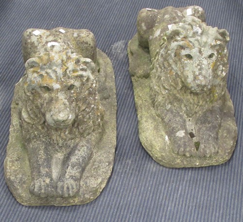 Lot 698 - A pair of composite stone recumbent lions on...