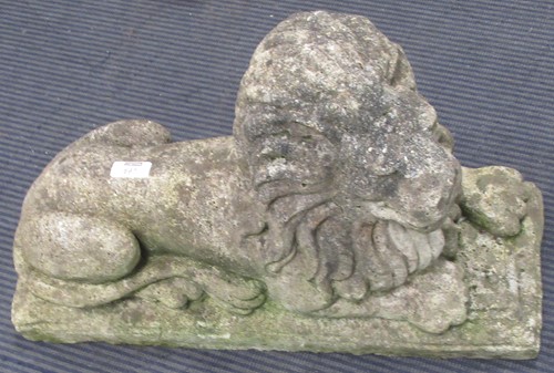 Lot 697 - A composite stone recumbent lion on integral...