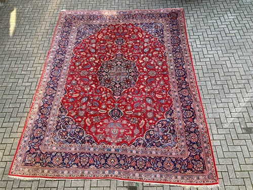 Lot 715 - A Persian red ground rug decorated with...