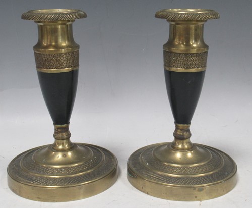 Lot 50 - A pair of Regency black and brass candlesticks...