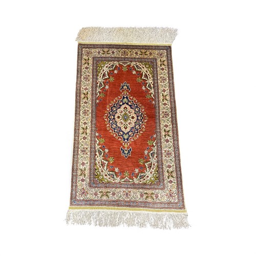 Lot 817 - A silk rug, with central medallion on a madder...