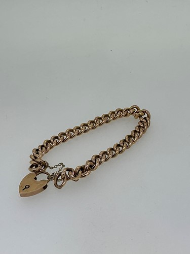 Lot 272 - A curb link bracelet with a heart shaped...