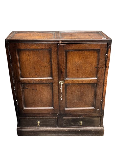 Lot 604 - A panelled oak two door cupboard of shaped...