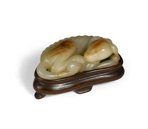 Lot 62 - A Chinese pale green and russet jade figure of a recumbent dog, probably Ming Dynasty