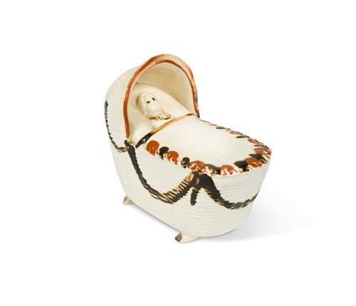 Lot 64 - A Bovey Pottery creamware cradle with a sleeping child, circa 1790