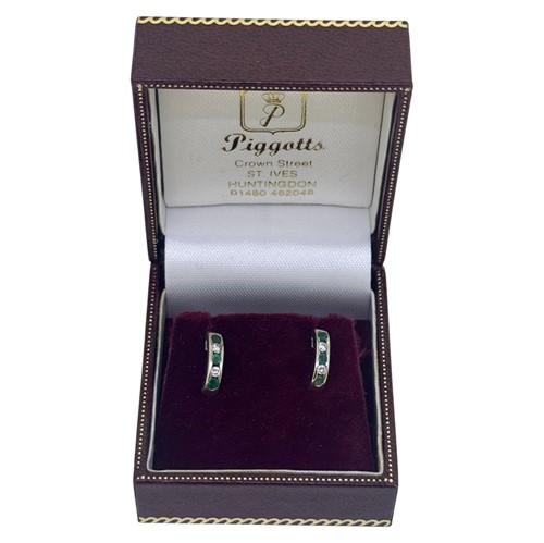 Lot 57 - A pair of emerald and diamond half hoop style...